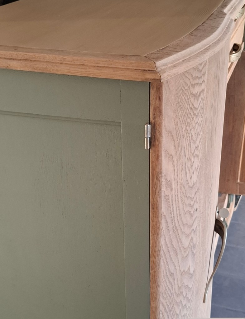 Vue d'un meuble en bois avec un dessus en bois clair et une porte peinte en vert.