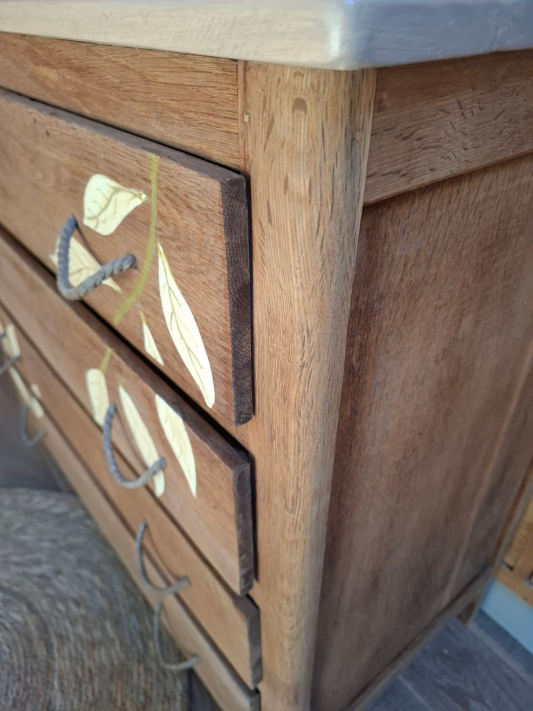 Détails d'une commode en bois avec des tiroirs ornés de feuilles.