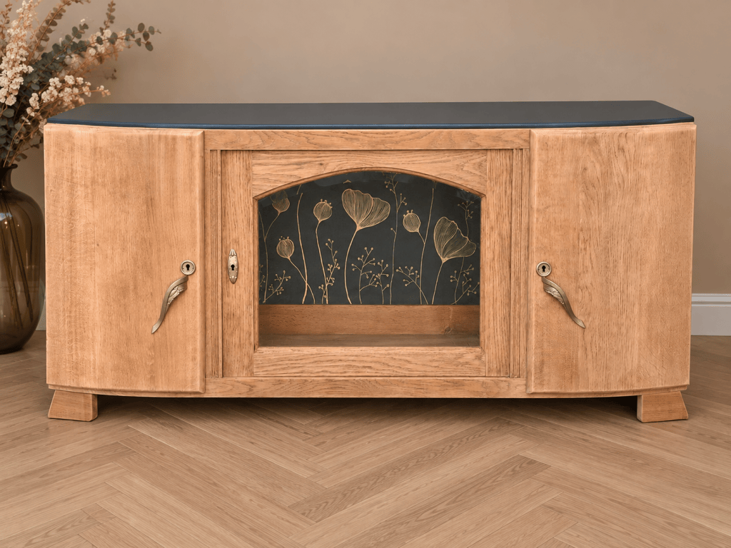 Meuble en bois clair avec un design élégant, porte en verre et décor floral sur fond sombre.