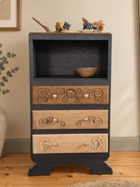 Un meuble de rangement en bois avec trois tiroirs ornés, un espace ouvert en haut et une petite assiette en bois à l'intérieur.
