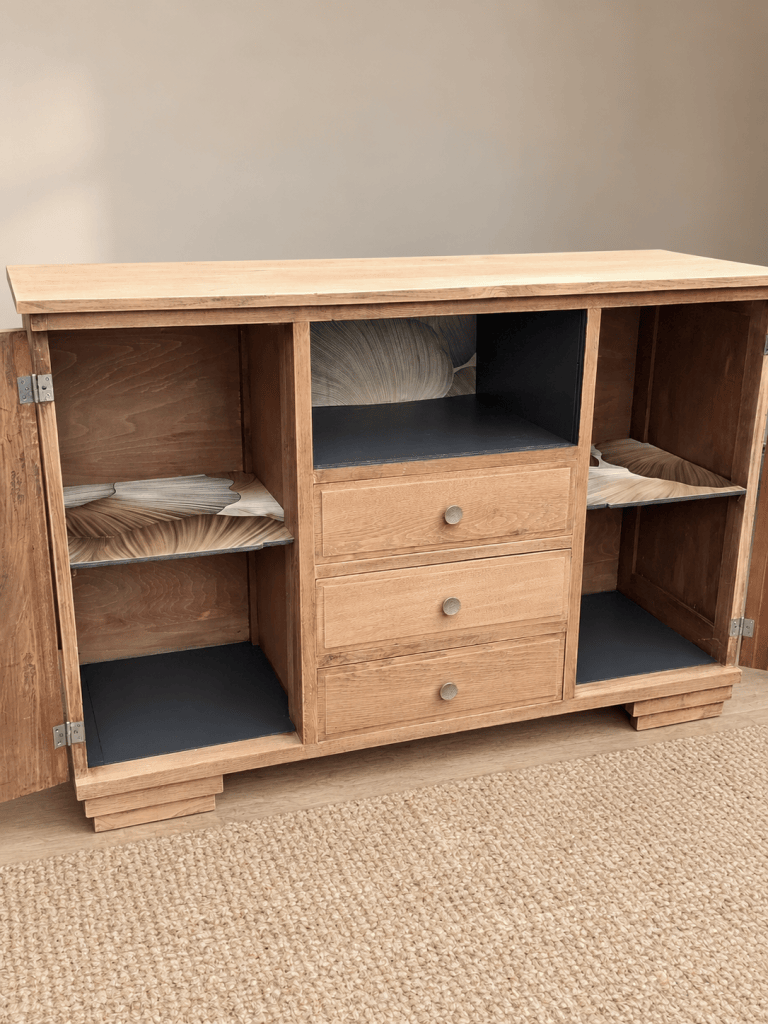 Meuble en bois avec des tiroirs et des étagères ouvertes, intérieur en couleur foncée, décoré de motifs ondulés.